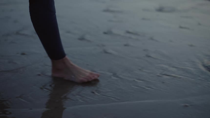 A person walking on a beach with a surfboard