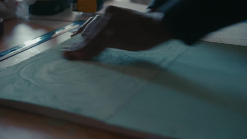 A close up of a person using sand paper on a piece of wood on a table