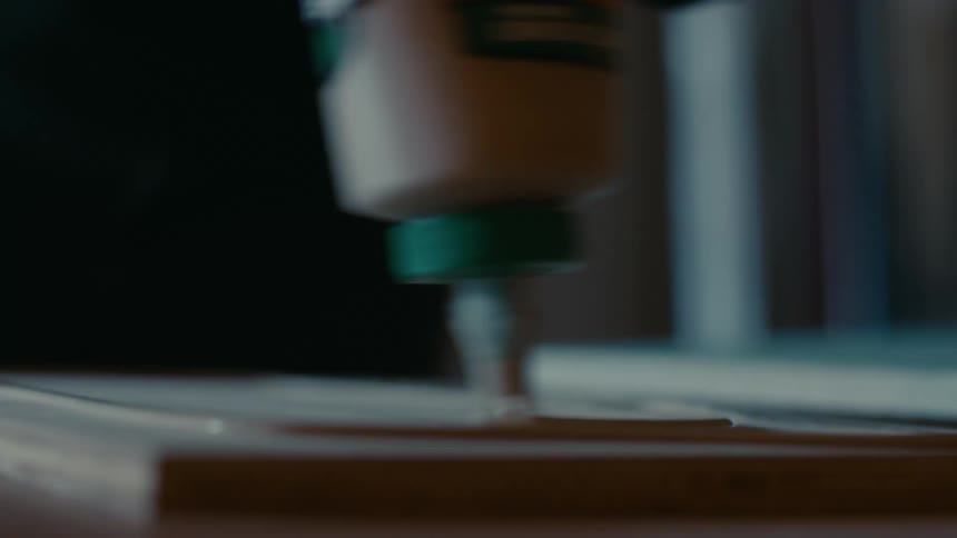 Person spreads glue onto surface of wooden square in workshop