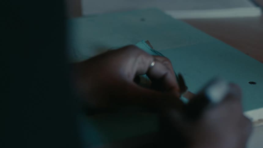 A close up of a person using a tool to peel away paper off a board