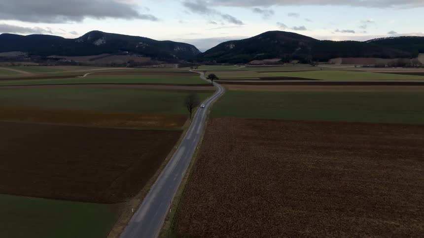 The view is of the nature area and you can see a car driving down the road
