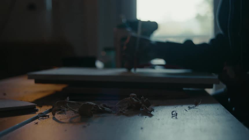 A person using a tool on a project they are working on laying on a wooden table