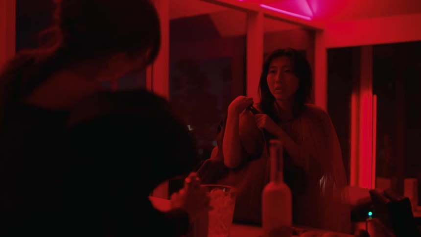 A tracking shot of a woman talking to a bartender in a red room