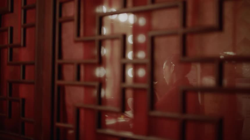 A woman sitting at her vanity is reflected off a red wall