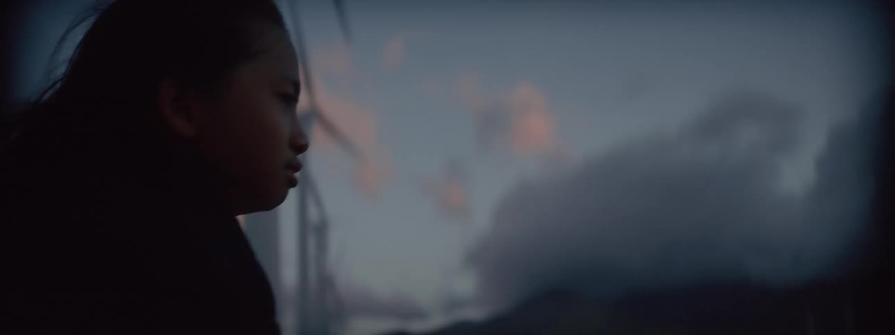 Close up of a woman walking against the wind near wind turbines at evening