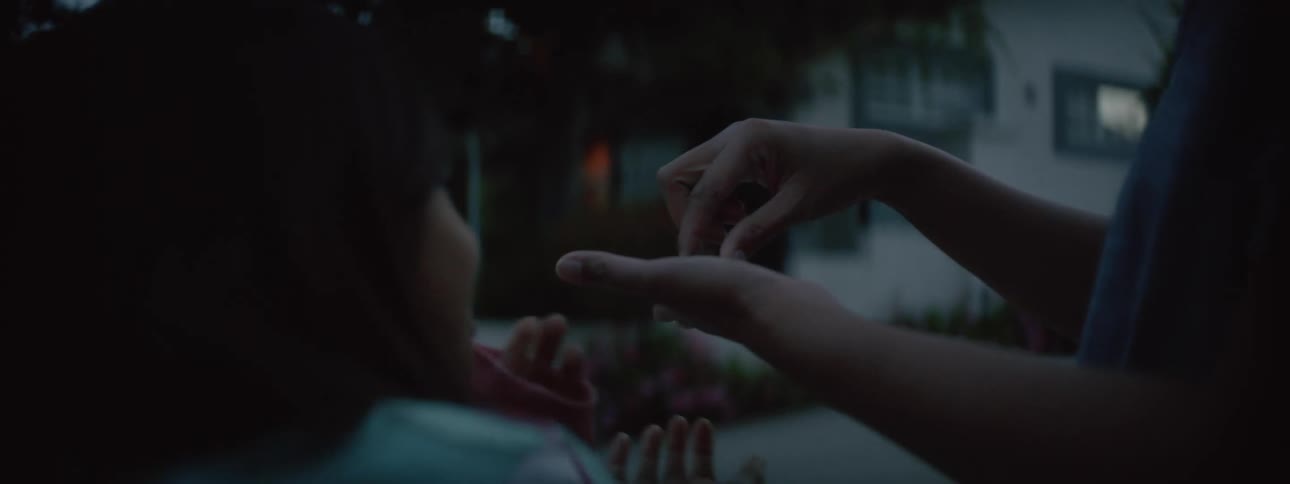 Daughter reaches for small animal mother is holding in her palm as they stand outdoors