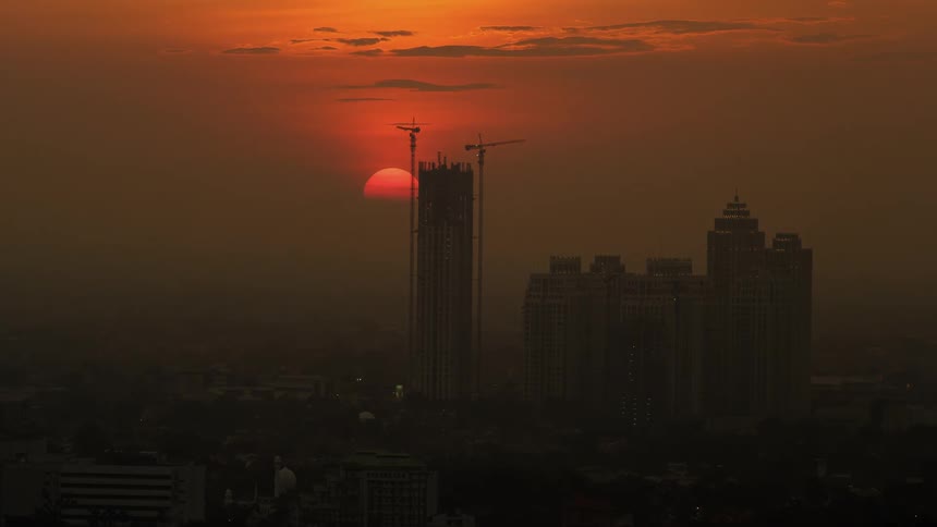 The sun going down over a city behind buildings