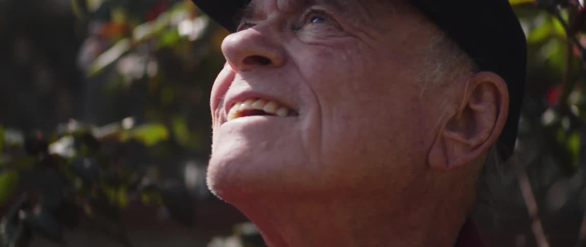 A close up of an elderly mans face as he looks up toward the sky smiling and squinting his eyes