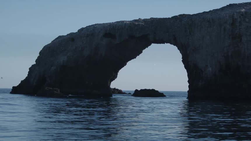 Arched rock formation above the ocean on a cloudless day