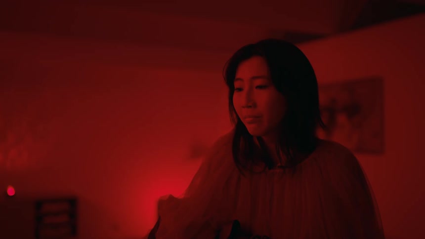 Young scared woman stands in the middle of a room bathed in red light
