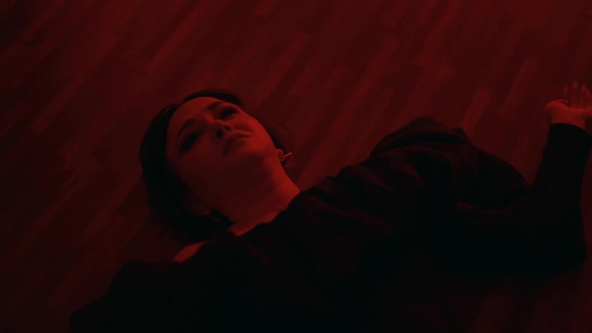 A young woman is lying on the floor and is crying