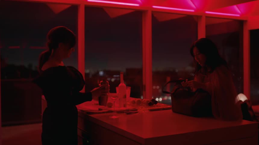 Friends have drinks in the bar of an apartment under red lights