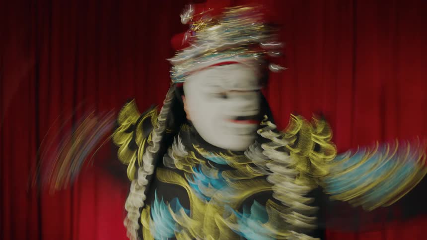 A person in a mask spins around on a stage