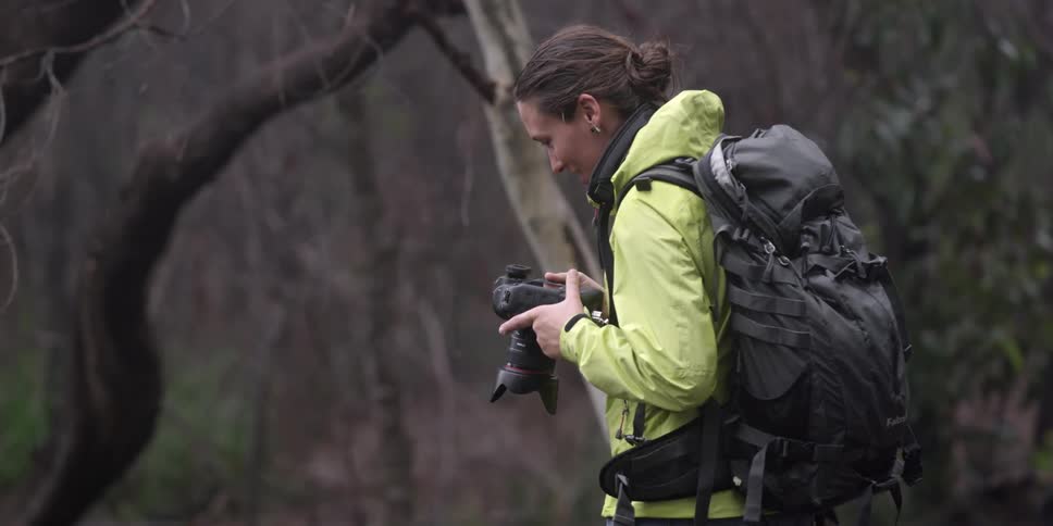 A woman looks at her camera and takes a photograph