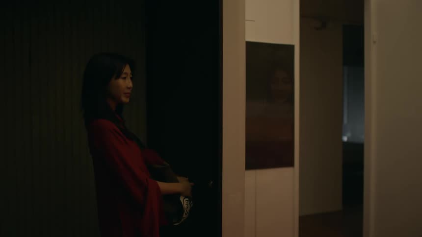 Young woman knocks on the door of an apartment before looking through the window next to it