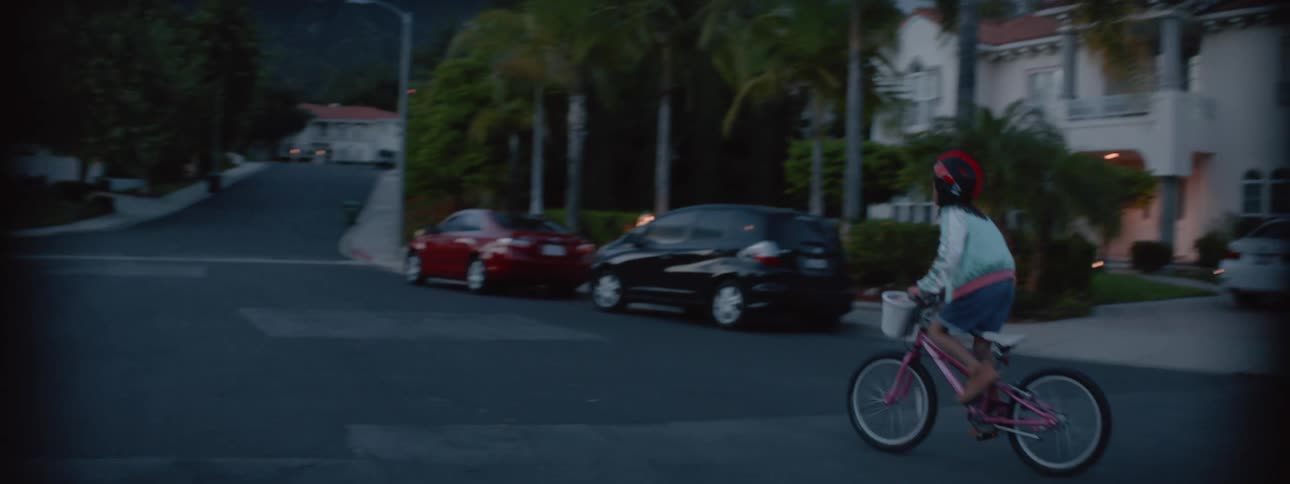 A young kid is riding her bike around the neighborhood