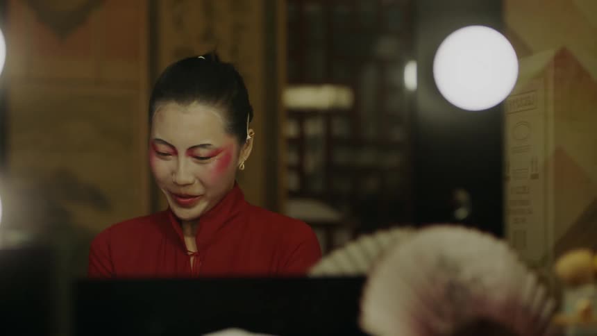 A nervous but happy asian woman is sitting at a vanity looking at herself in the mirror