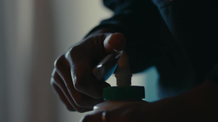 A person uses a box cutter to cut the tip off a plastic bottle
