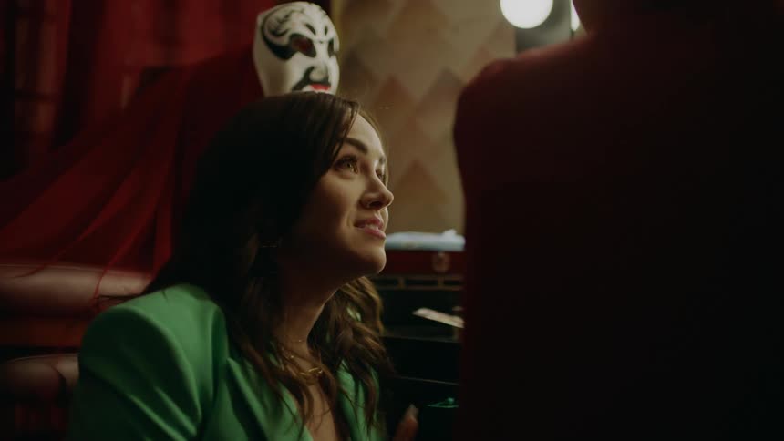 A woman knelt down in a green suit smiling talking to someone next to her