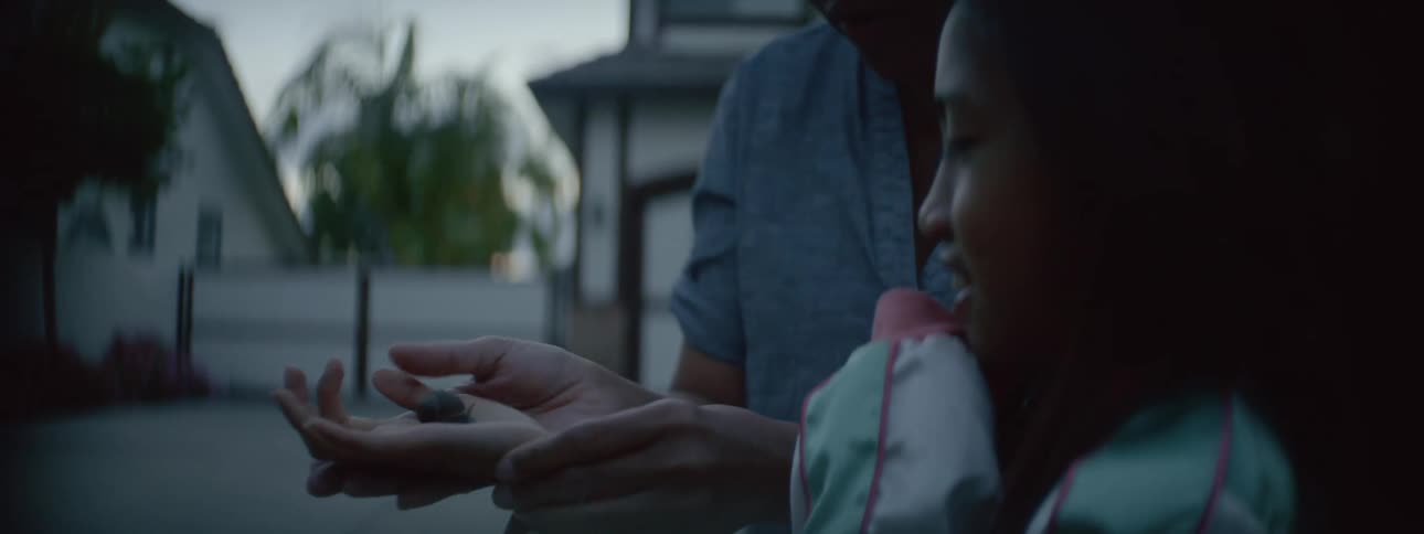 A mother and daughter admire a snail they are holding outside of their suburban home