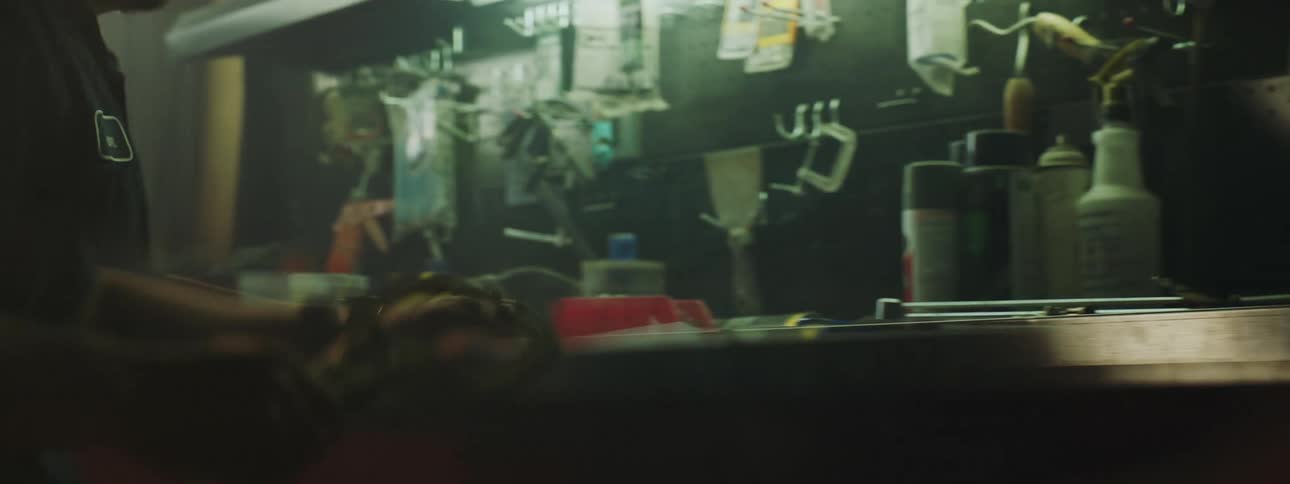 Close up of the hands of a mechanic working on a dimly lit workshop