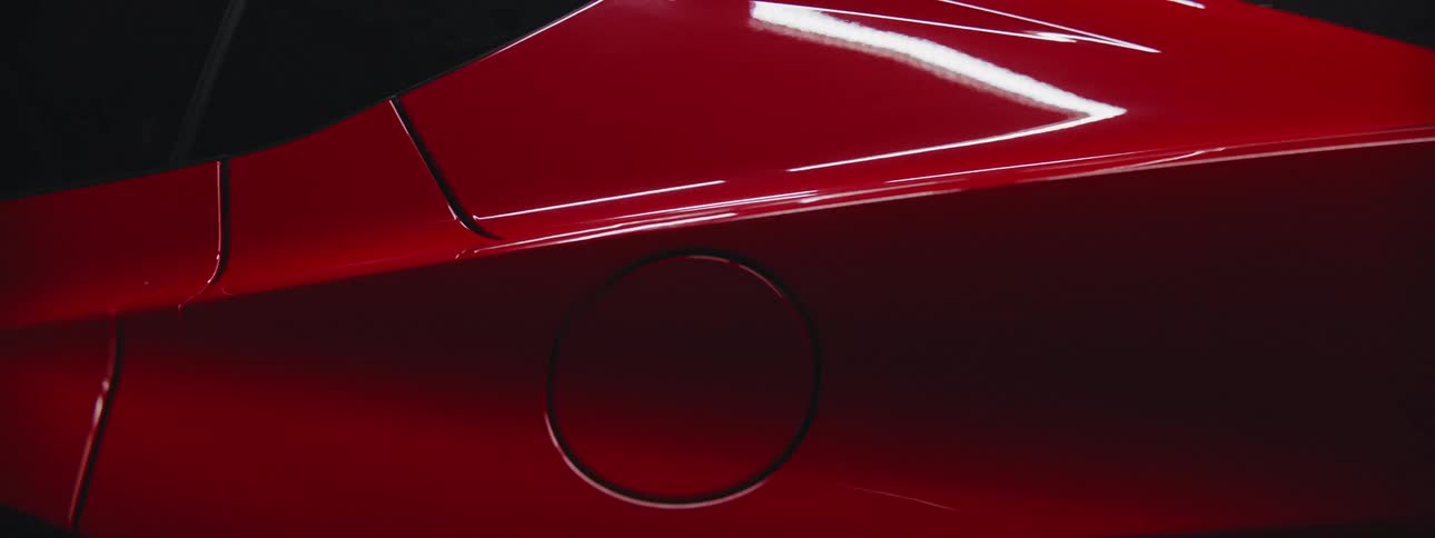 The view is of a portrait of a red car that is driving