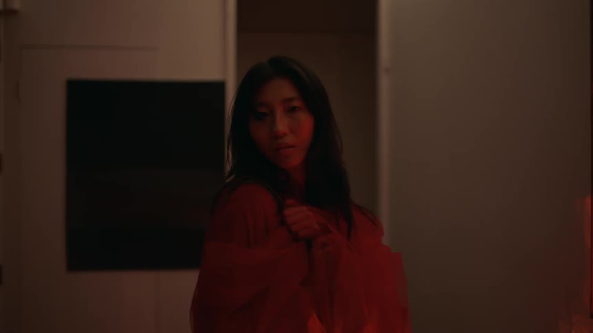 A woman is walking through a room toward the door when she stops and turns around and walks back in