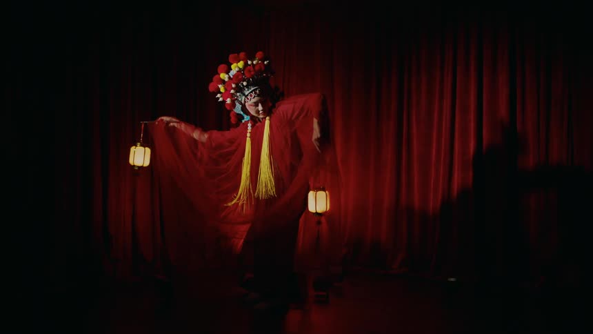 Woman wearing opera costume performs on stage under a spotlight