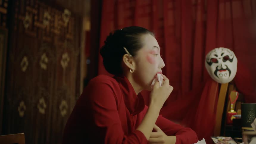 Actress sitting on a dressing room applies makeup for a chinese theatre performance