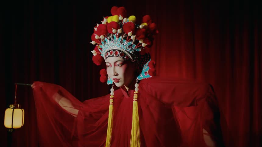 A woman performing on stage wearing a red costume holding lanterns in her hands