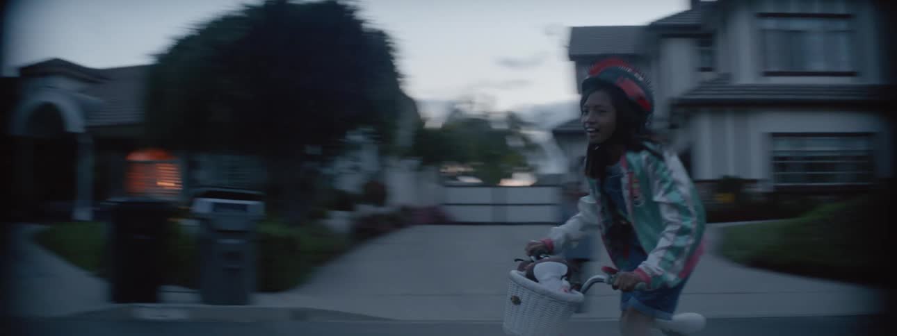 A young kid is outdoors and is riding her bike outside