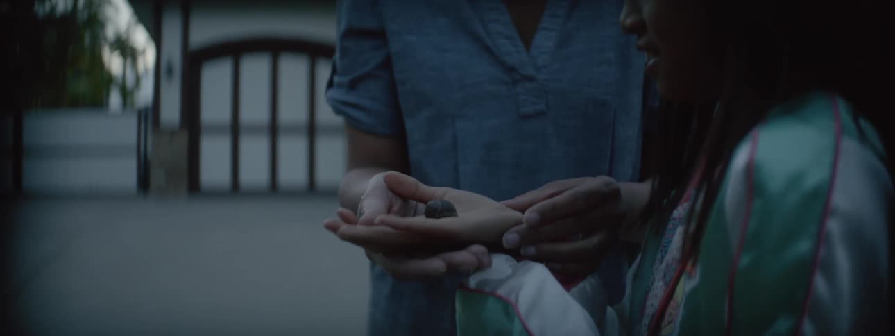 A young girl standing next to her mother holding something in her hands