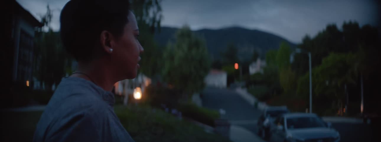 A woman watching a child outside in a suburban neighborhood