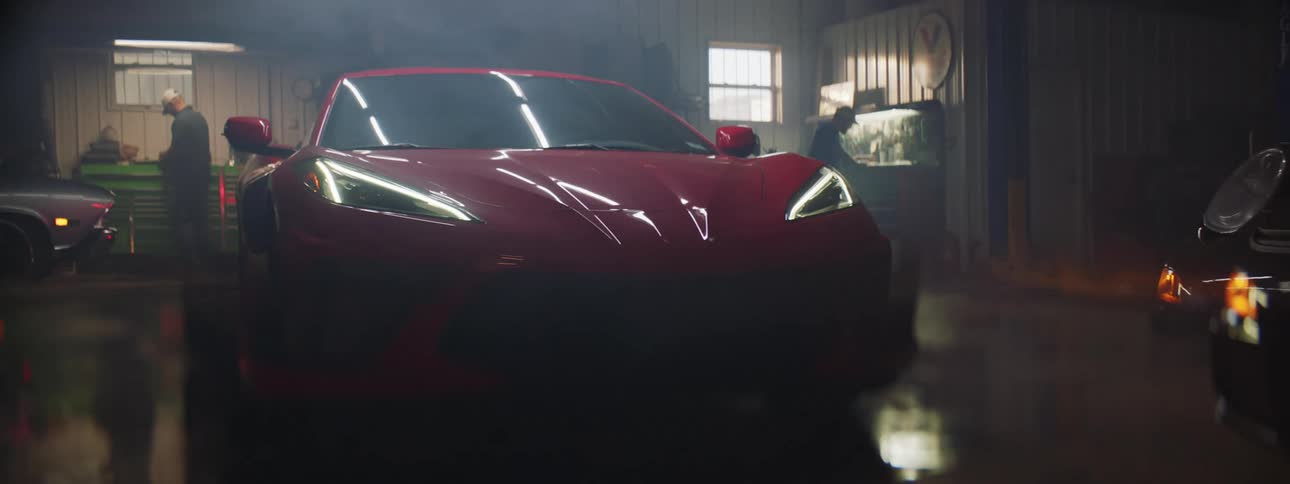 Red sports car turns on headlight at a garage