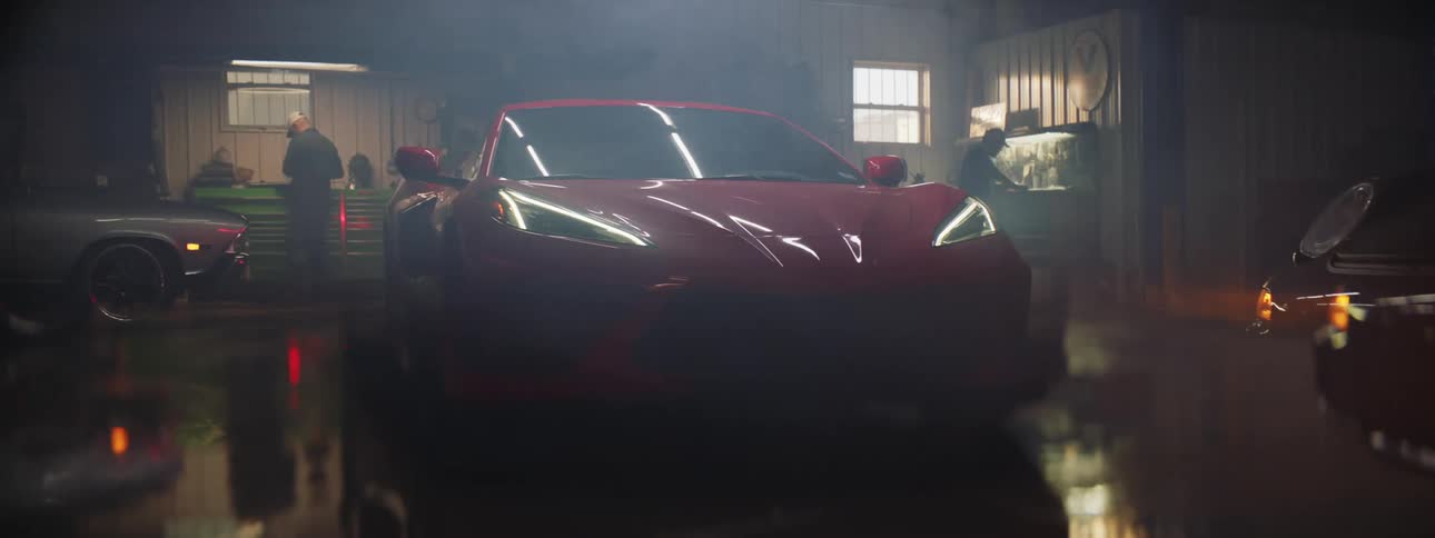 Close up of a red luxury sports car turning headlights on inside a repair shop