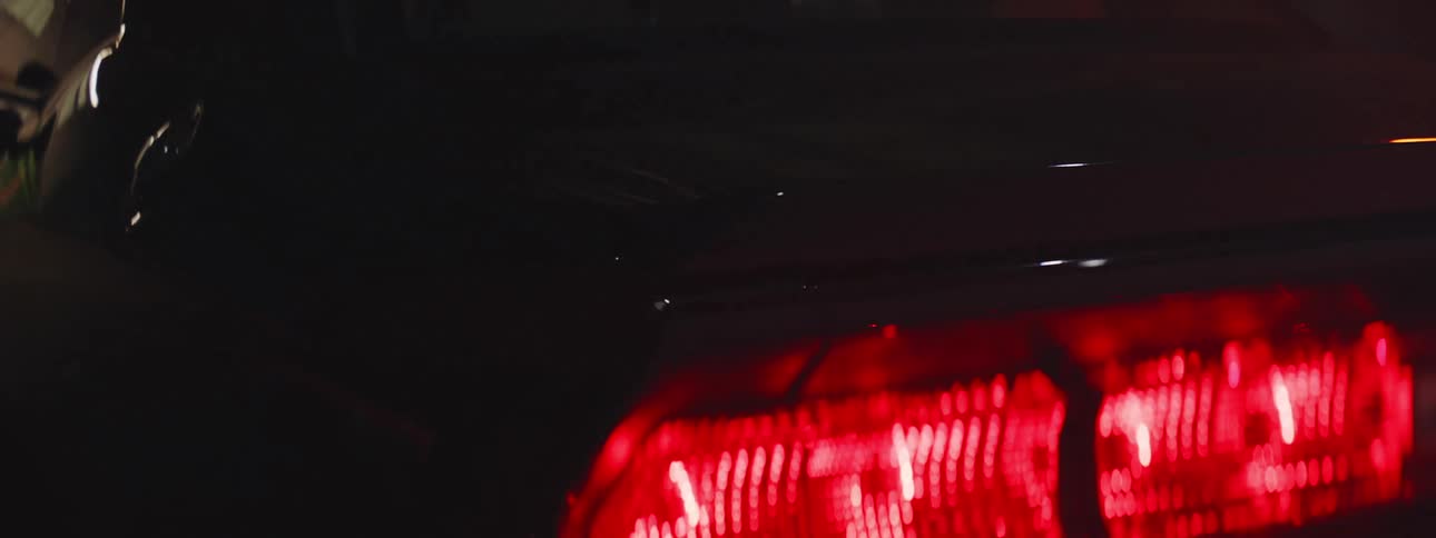 Light and shadows flicker across the back end of a car and the tail lights