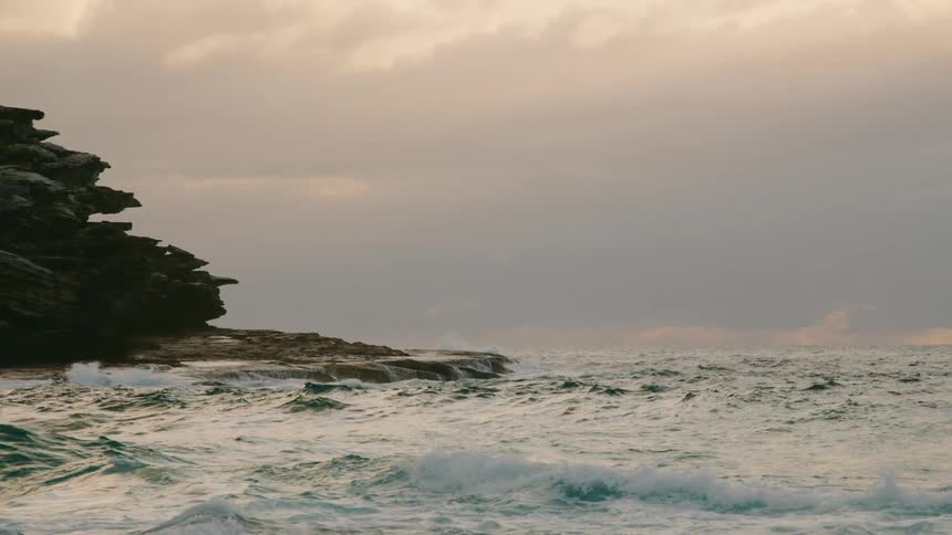 Rough water waves splash as they roll in to a rocky shoreline