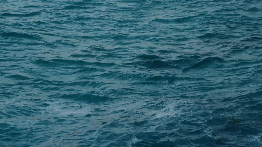 Light shines and reflects on rough water was it waves and moves
