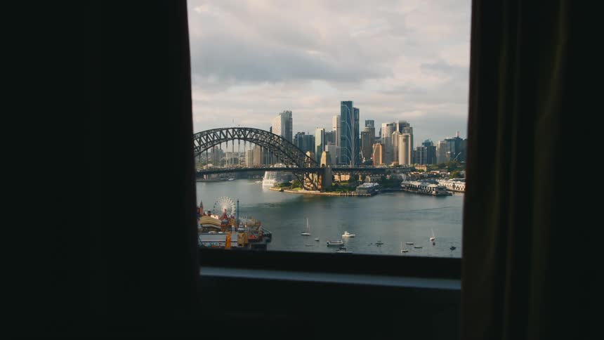 A view through a window of a city skyline of buildings and an arch bridge over a waterway around the city