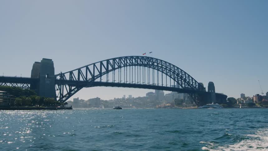 Arch bridge over a river near the city skyline at daytime seen from a moving boat