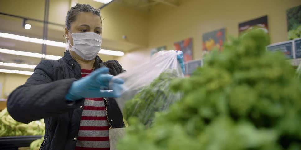 Woman wearing face mask and latex gloves grocery shopping