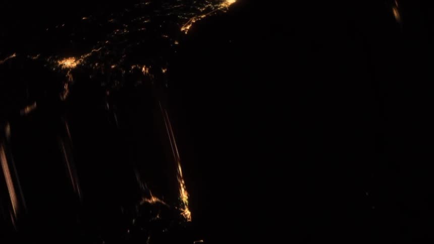 Distorted footage of city lights and lightning flashes at night seen from space