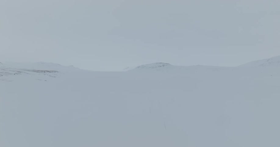 A team of three ski touring with pulkas through a frozen hilly landscape