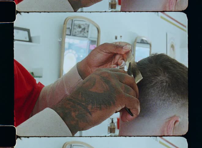 A young man is a barber and giving a man a hair cut