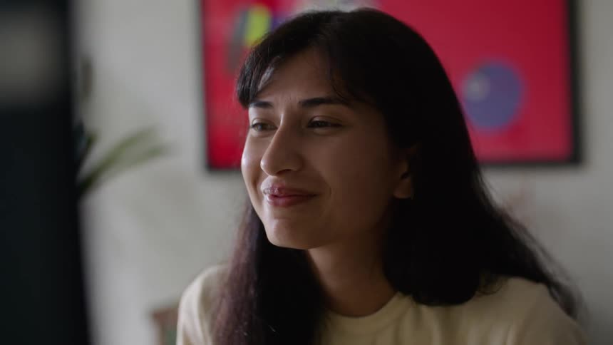 Woman working in office nods and smiles after examining computer screen