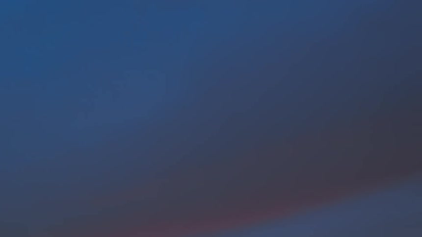 Sunlight shines on clouds as they turn pink moving across the sky and grow darker as the sun sets