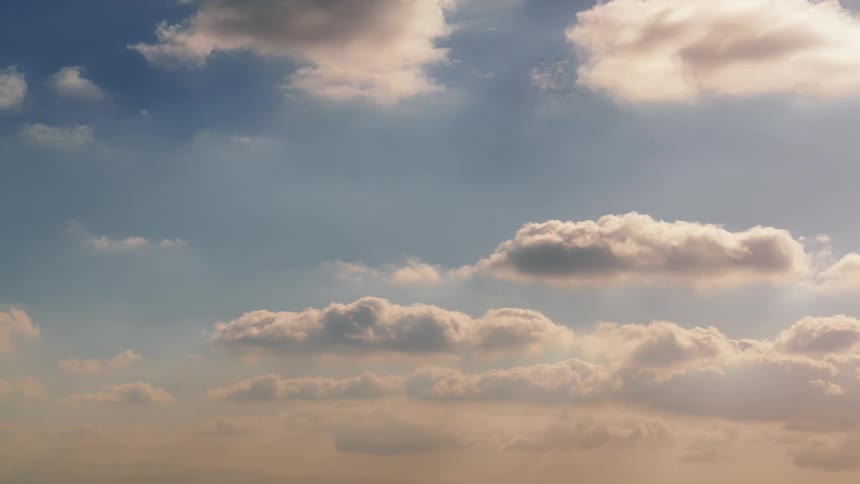 The sun shines on cumulus clouds as they float across the sky