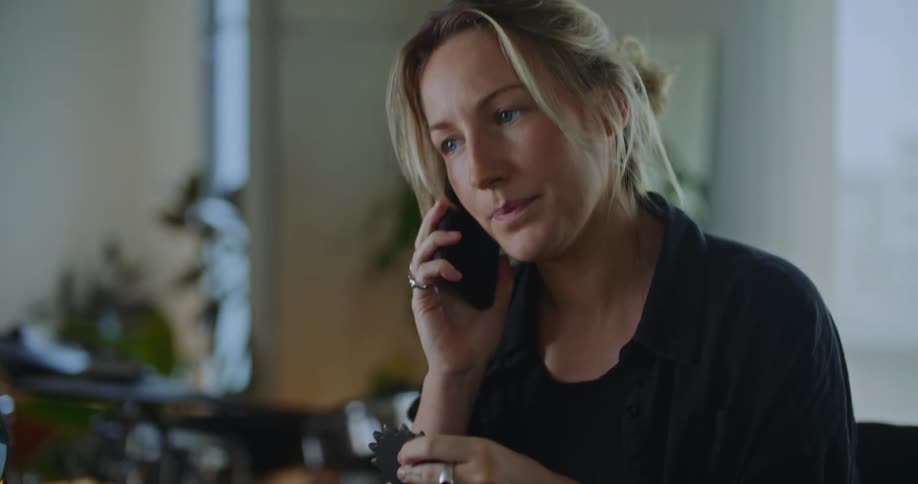 A woman is talking on her cell phone as she holds a round gear in her hand