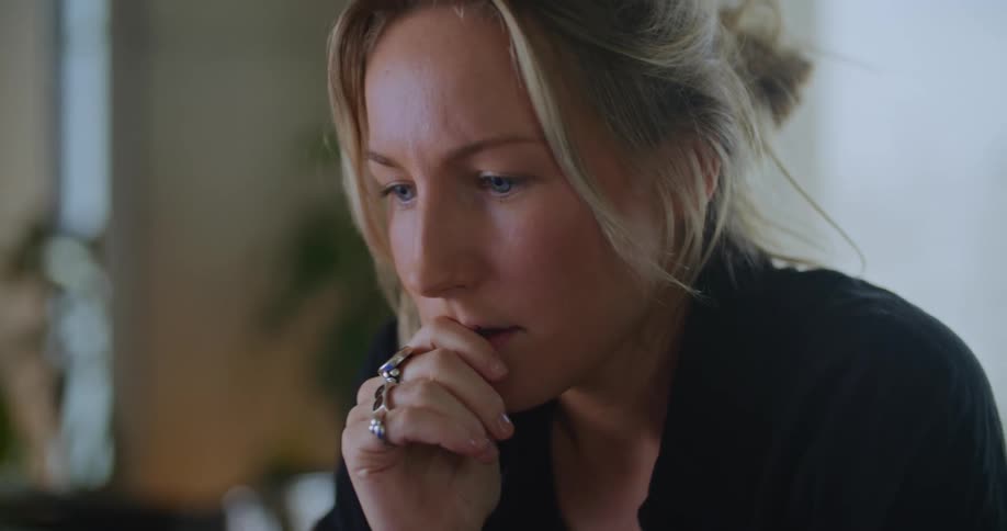 A woman is typing on a laptop computer and she stops to think and then continues to type with one hand