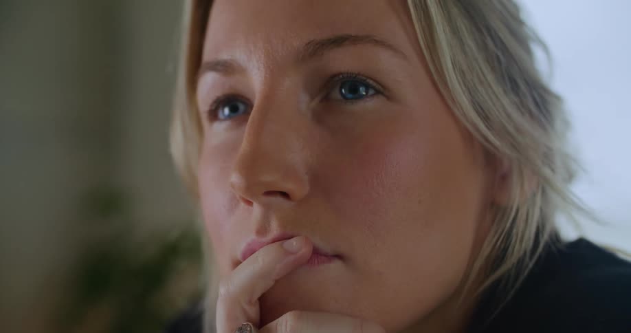 Close up of the face of a young blonde woman with blue eyes thinking